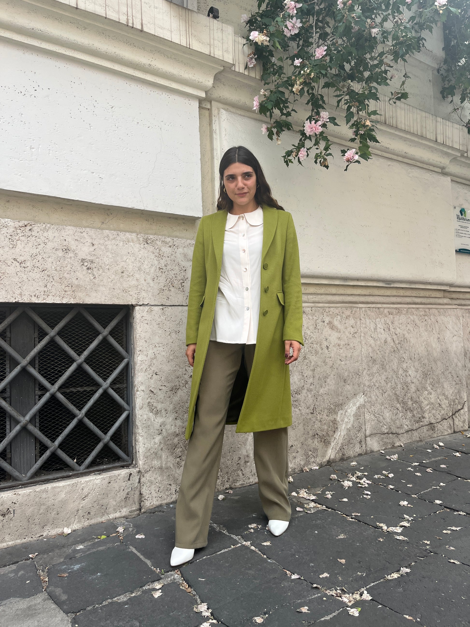  "Testo Alternativo: Cappotto Slim Fit Anastasia - Verde Pistacchio in Lana Cashmere e Viscosa. Bordature interne in raso rifinite a mano, abbottonatura semplice a tre bottoni, polso con bottoni e due tasche. Foderato per un comfort extra. Realizzato in sartoria con disponibilità per taglie, garantendo qualità e esclusività. La modella alta 1,70 m indossa la taglia 44, leggermente morbida per un look confortevole. Aggiungi un tocco regale al tuo stile con il Cappotto Anastasia di EVITA."