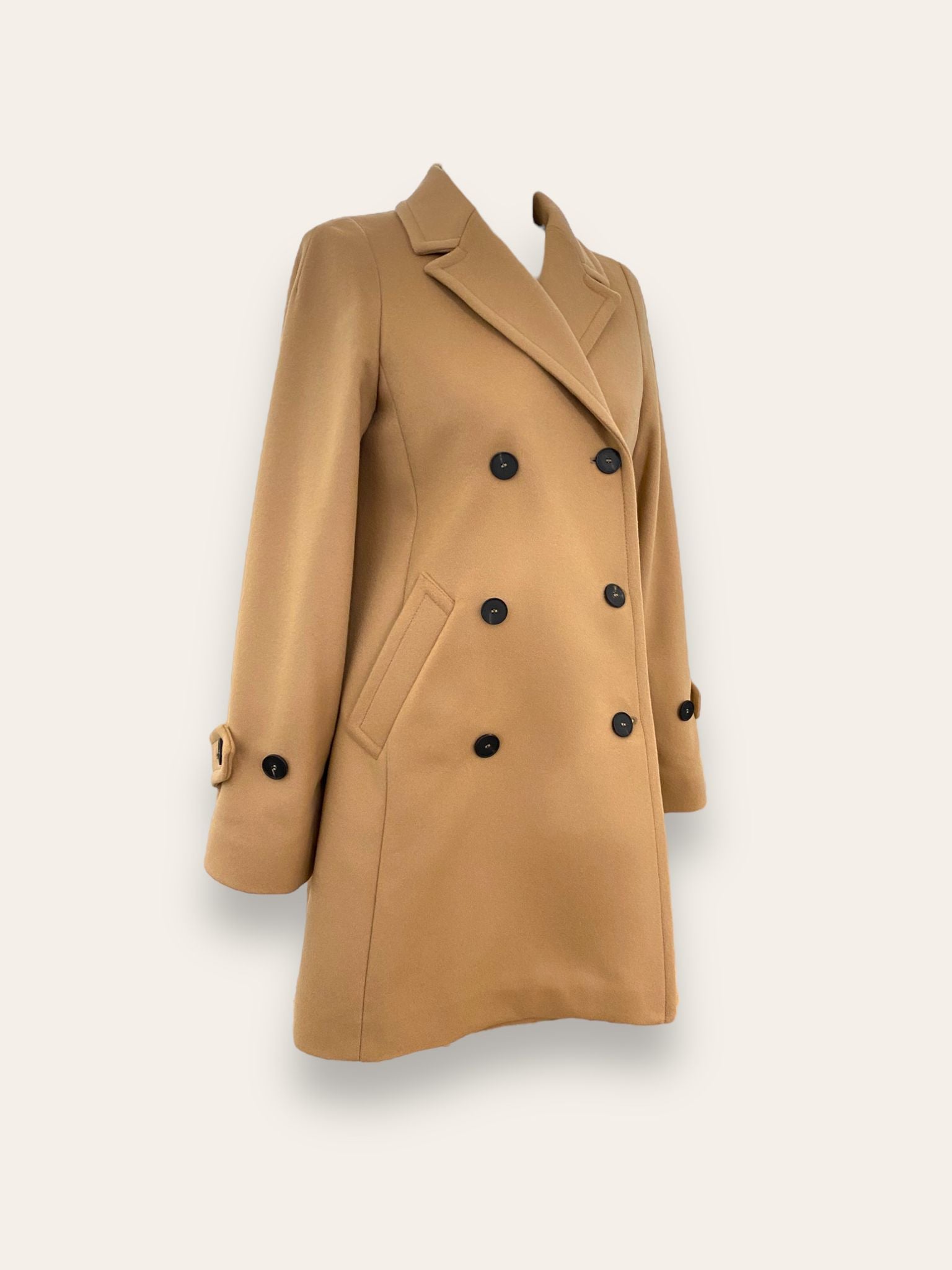 Scopri il cappotto trench Elvira color cammello di EVITA, realizzato con un pregiato mix di lana, poliammide e cashmere. Con il suo design classico e i bottoni neri, rappresenta l'artigianato italiano di alta qualità. Perfetto per un look sofisticato e senza tempo. Prodotto con passione da EVITA, made in Italy.