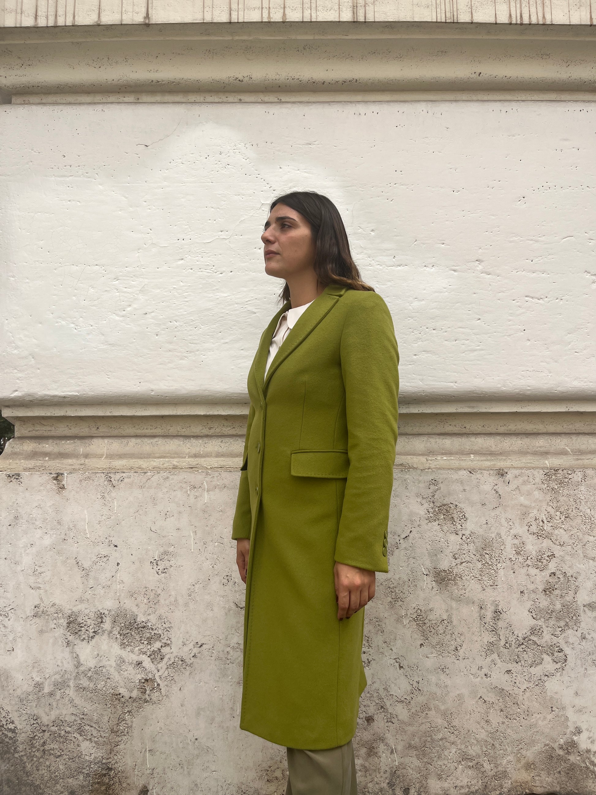  "Testo Alternativo: Cappotto Slim Fit Anastasia - Verde Pistacchio in Lana Cashmere e Viscosa. Bordature interne in raso rifinite a mano, abbottonatura semplice a tre bottoni, polso con bottoni e due tasche. Foderato per un comfort extra. Realizzato in sartoria con disponibilità per taglie, garantendo qualità e esclusività. La modella alta 1,70 m indossa la taglia 44, leggermente morbida per un look confortevole. Aggiungi un tocco regale al tuo stile con il Cappotto Anastasia di EVITA."