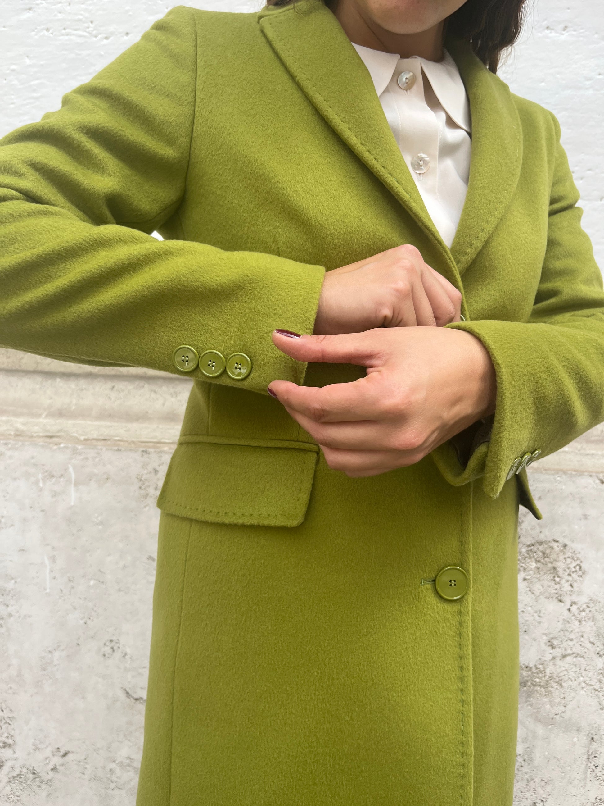  "Testo Alternativo: Cappotto Slim Fit Anastasia - Verde Pistacchio in Lana Cashmere e Viscosa. Bordature interne in raso rifinite a mano, abbottonatura semplice a tre bottoni, polso con bottoni e due tasche. Foderato per un comfort extra. Realizzato in sartoria con disponibilità per taglie, garantendo qualità e esclusività. La modella alta 1,70 m indossa la taglia 44, leggermente morbida per un look confortevole. Aggiungi un tocco regale al tuo stile con il Cappotto Anastasia di EVITA."