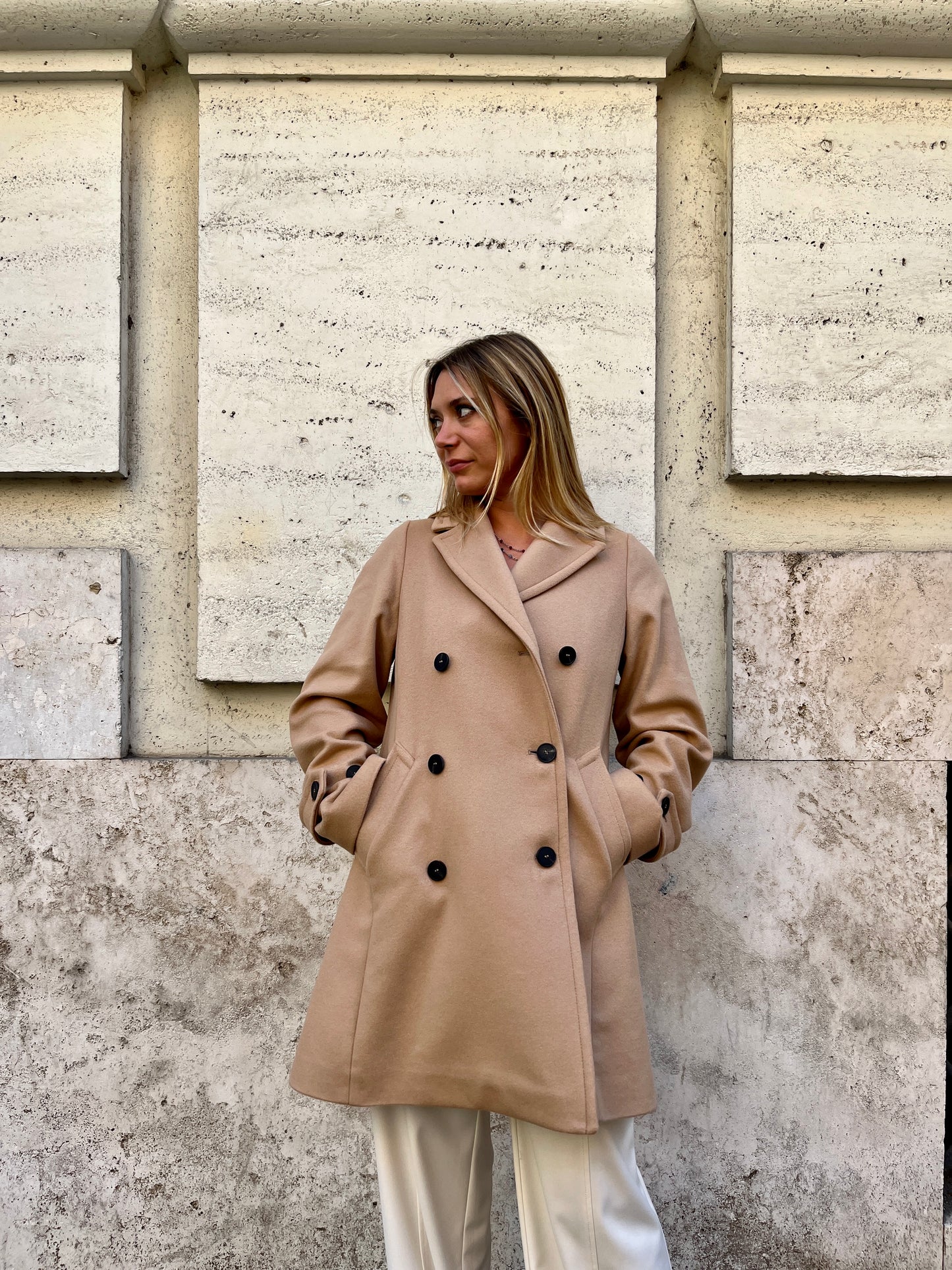 Scopri il cappotto trench Elvira color cammello di EVITA, realizzato con un pregiato mix di lana, poliammide e cashmere. Con il suo design classico e i bottoni neri, rappresenta l'artigianato italiano di alta qualità. Perfetto per un look sofisticato e senza tempo. Prodotto con passione da EVITA, made in Italy.